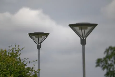 Two elegant metal lanterns shaped like triangles under a rainy sky Stock Photos