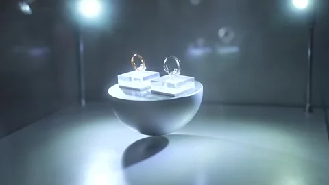 Two elegant wedding rings, one gold and one silver, rotating on a sleek, modern Stock Footage 328988288