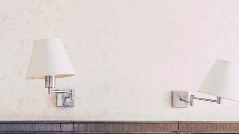 Two elegant white wall sconces mounted on a plain wall Stock Photos