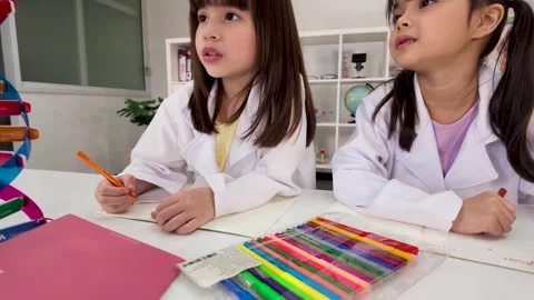 Two Elementary School Girls in Science Lab Coats Writing in Classroom Stock Footage 345487925