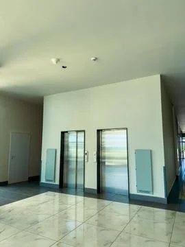 Two elevators are in a hallway of a building. The setting is well-lit with gr Stock-Fotos