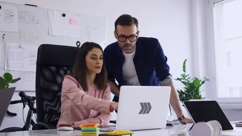 Two employees discussing at office looking on laptop Stock Footage 102860158