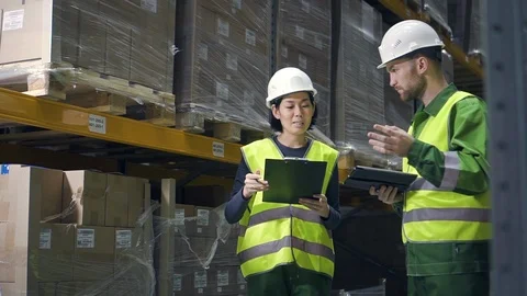 Two employees discussing work with tablet and clipboard at logistics center Stock Footage 124824497