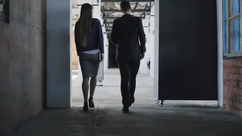 Two employees enter the creative office space, greet colleagues and sit down at Stock Footage 109500258