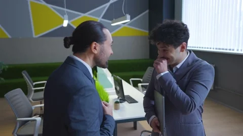 Two employees, men in suits in the office laughing, talking cheerfully. Stock Footage 233993778