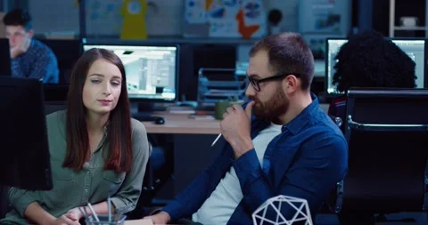 Two employees sitting at computer and discussing project issues. Beautiful woman Stock Footage 140289477
