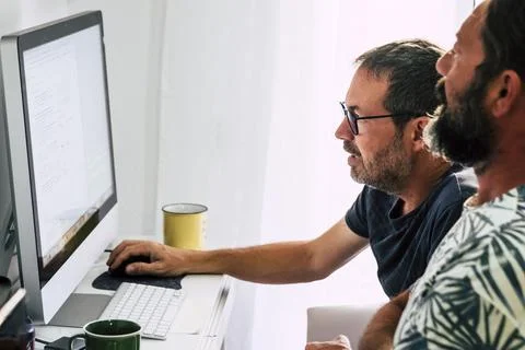 Two employees working on desktop computer together. Mature men working as a t Stock Photos