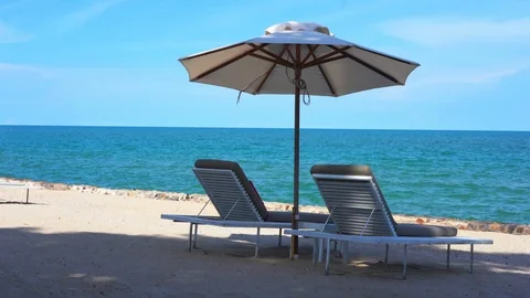 Two empty beach chairs and an umbrella on a tropical ocean beach. Mid day. Vídeos de archivo 116765785