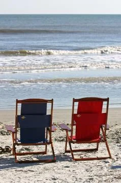 Two empty beach chairs at the foot of the ocean Stock Photos