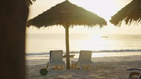 Two empty beach sun beds or chairs by tropical coast in tourist resort in Africa Stock Footage 307718690