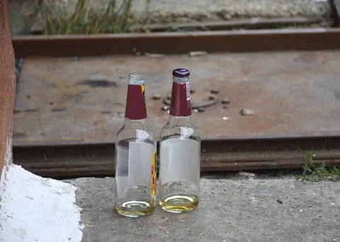 Two empty beer bottles on the street near the curb Stock Photos