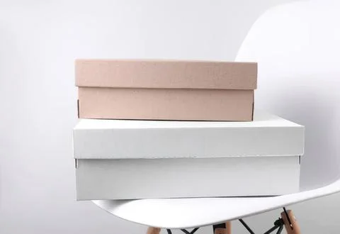 Two empty cardboard boxes stacked on a white chair Stock Photos