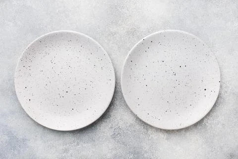 Two empty ceramic plates on a light concrete background. Top view. Stock-Fotos