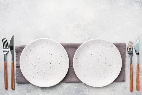 Two empty ceramic plates on a light concrete background. Top view. Stock-Fotos