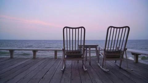 Two empty chairs on a beach with sunset sky and clouds Stock Photos