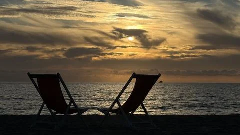Two Empty Chairs Facing Ocean Sunset on Beach Stock Photos