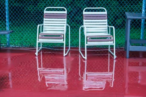 Two empty chairs reflect on the rain soaked deck Stock Photos