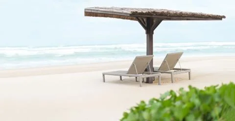 Two empty chaise longues under shed on beach. Stock Photos