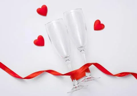 Two empty champagne glasses with red hearts and ribbon 스톡 사진