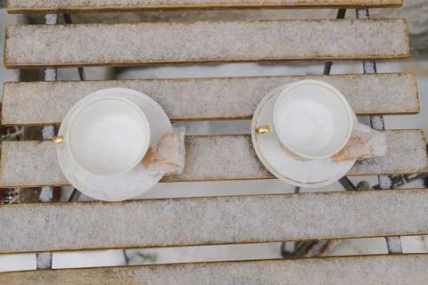 Two empty coffee cups covered with fresh snow on wooden table Stock Photos