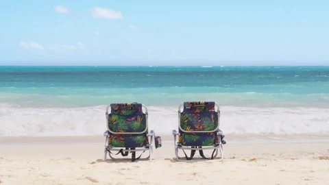 Two empty colorful beach chairs facing beautiful blue ocean, Cinematic travel 4K Stock Footage 260529343