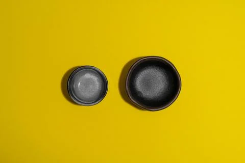 Two empty dark plates on yellow background Foto stock