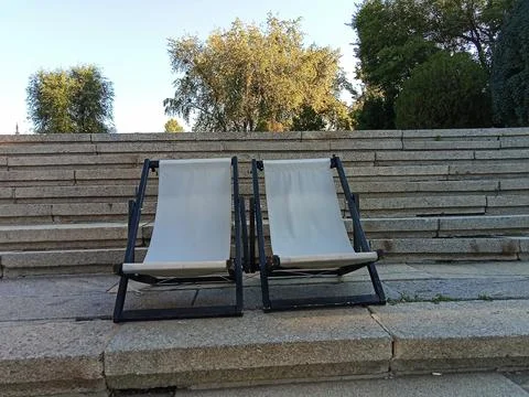 Two Empty Deck Chairs on Stone Steps in a Park Stock Photos