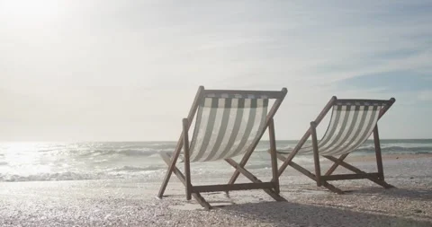 Two empty deckchairs standing on beach at sunset Stock Footage 340765919