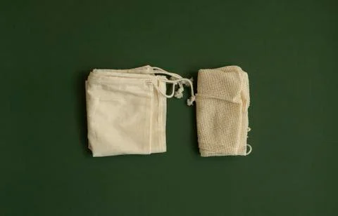 Two empty eco friendly cotton reusable shopping bags on green surface. Plastic Stock Photos