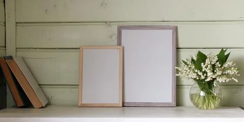 Two empty frames on the table and lilies of the valley, a rural mockup. cop.. Stock Photos