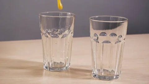 Two empty glass filled refresh orange juice slowmotion white background closeup Stock Footage 113072967