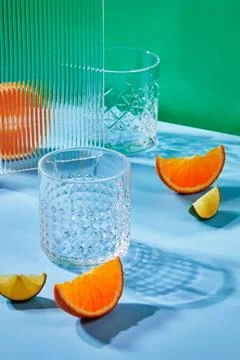 Two empty glass glasses on colored backgrounds with shadows from sunlight Stock Photos