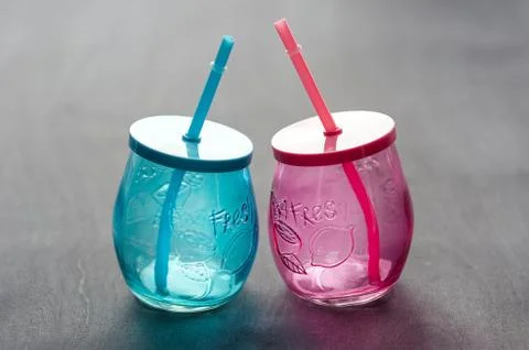 Two empty glasses, made of blue and red glass with straws Stock Photos