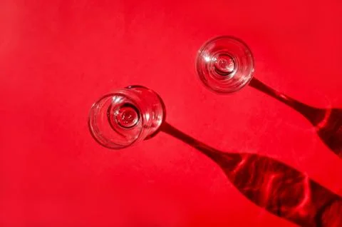 Two empty glasses with shadows on red background in natural sunlight . Stock-Fotos