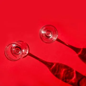 Two empty glasses with shadows on red background in natural sunlight . Stockfoto's