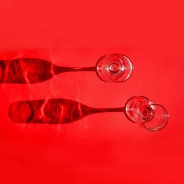 Two empty glasses with shadows on red background in natural sunlight . Stockfoto's
