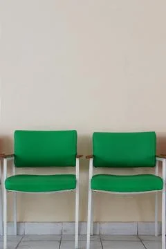 Two empty green chairs. Plain wall background Stock Photos