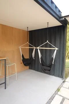 Two empty hammocks hanging from ceiling in modern patio Stock Photos