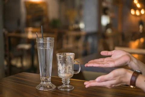 Two empty iced coffee cups in coffee shop and hands showing on glasses Stock Photos