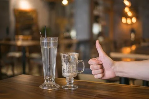 Two empty iced coffee glass cups on the table and hand showing thumbs up sign Stock Photos