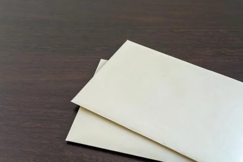 Two empty paper sheets on a dark wooden table surface. Blank envelopes Stock Photos