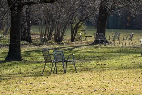 Two empty park chairs on grass with trees and woodland background Stock Photos