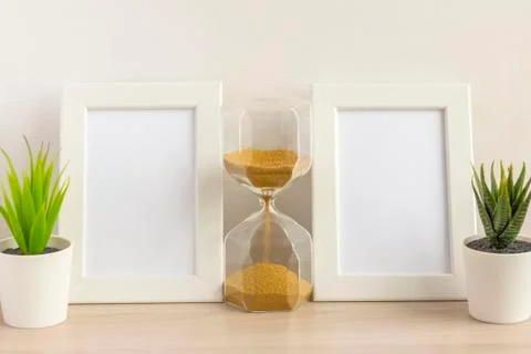 Two empty photo frames and an hourglass on a table or shelf with a copy of th Stock Photos