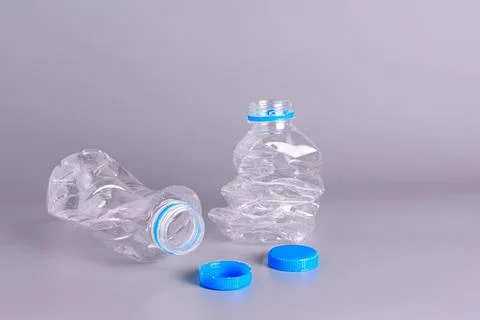 Two empty plastic water bottles with caps on gray background Stock Photos