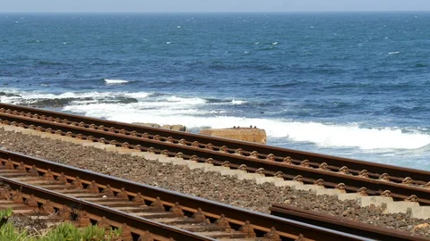 Two empty railway tracks blue ocean rocky seashore &amp; horizon to sky 스톡 동영상 102342797