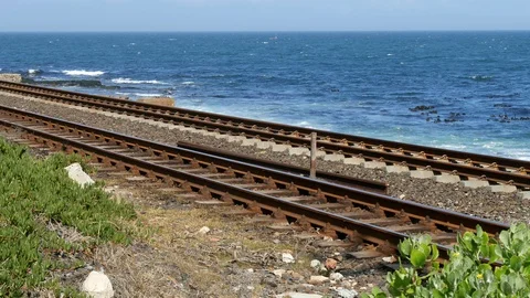 Two empty railway tracks blue ocean horizon &amp; small boat 스톡 동영상 102343543