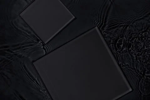 Two empty square podiums on transparent black water background Foto stock