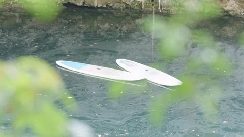 Two empty stand up paddleboards floating aimlessly on calm water Stockbeeldmateriaal 340272961