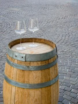 Two empty stemware on a  wooden barrel. Paver blocks background Stock Photos