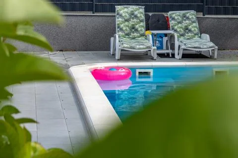 Two Empty Sun Loungers by a Clean Swimming Pool at an Exclusive Apartment i.. Stock Photos
